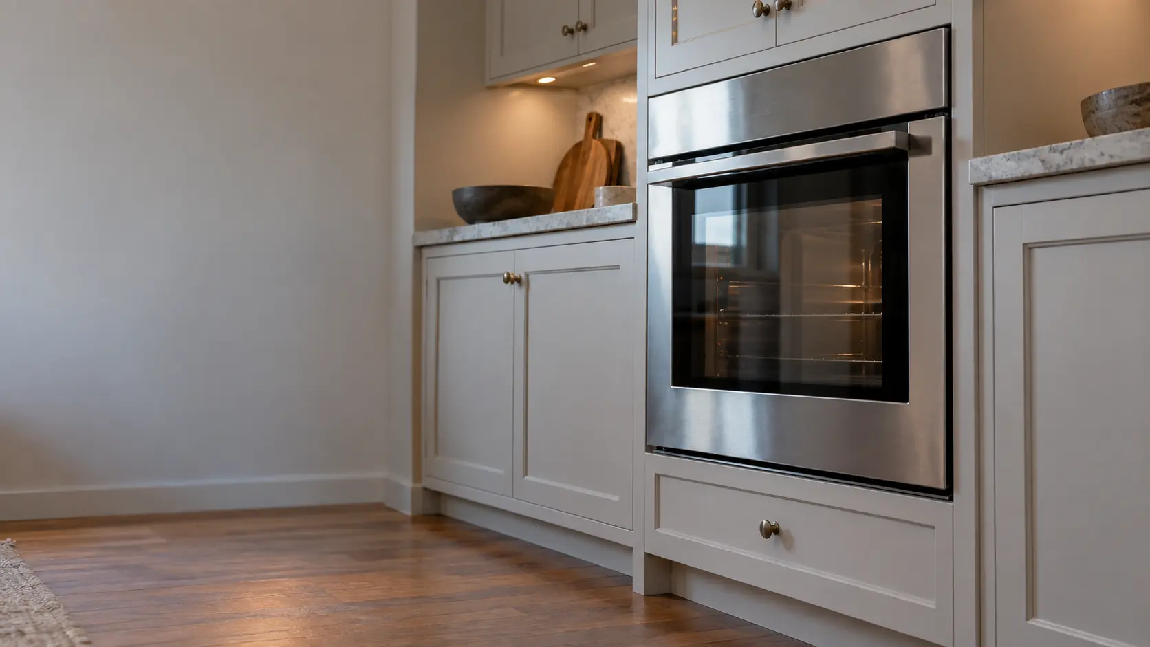 A kitchen wall with the oven in a prewar co-op kitchen with a compact wall oven, seen from a low angle, the oven door glass catching the light.