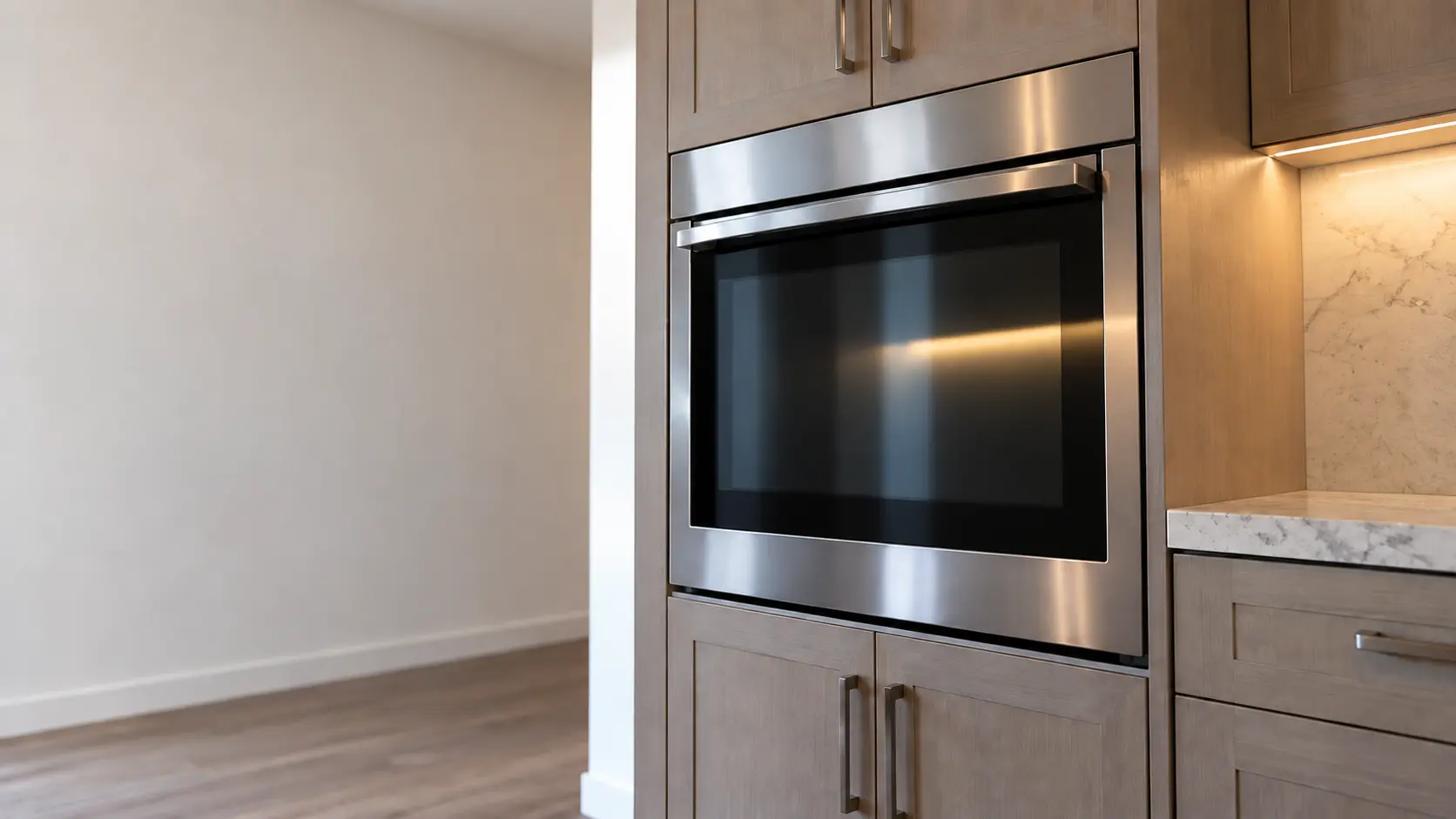 A kitchen wall with the oven in a block house kitchen with a single wall oven, seen from a low angle, the oven door glass catching the light.
