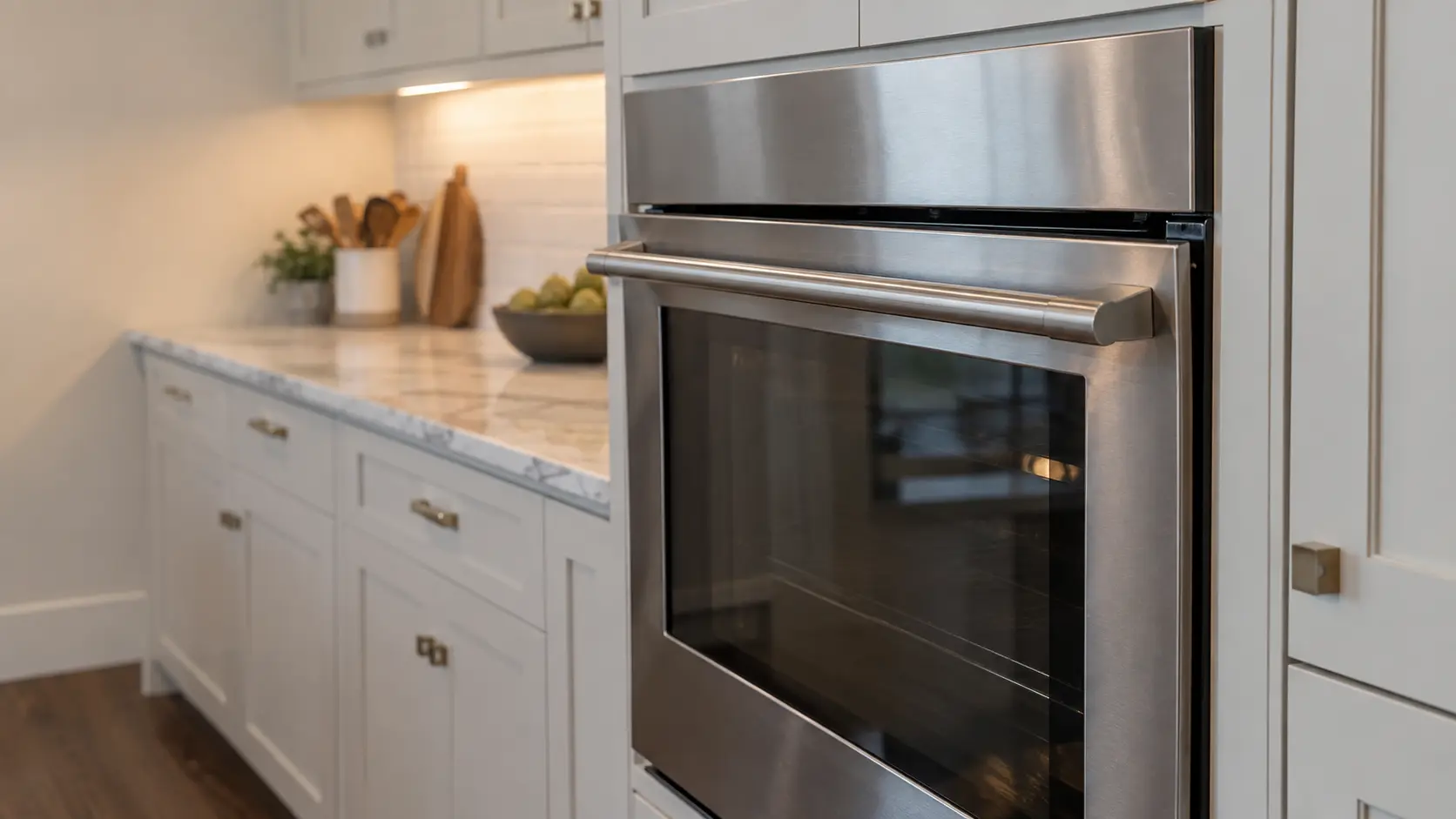 The side of a single wall oven in a US home kitchen with its door hanging slightly crooked and a narrow gap showing along the top edge.