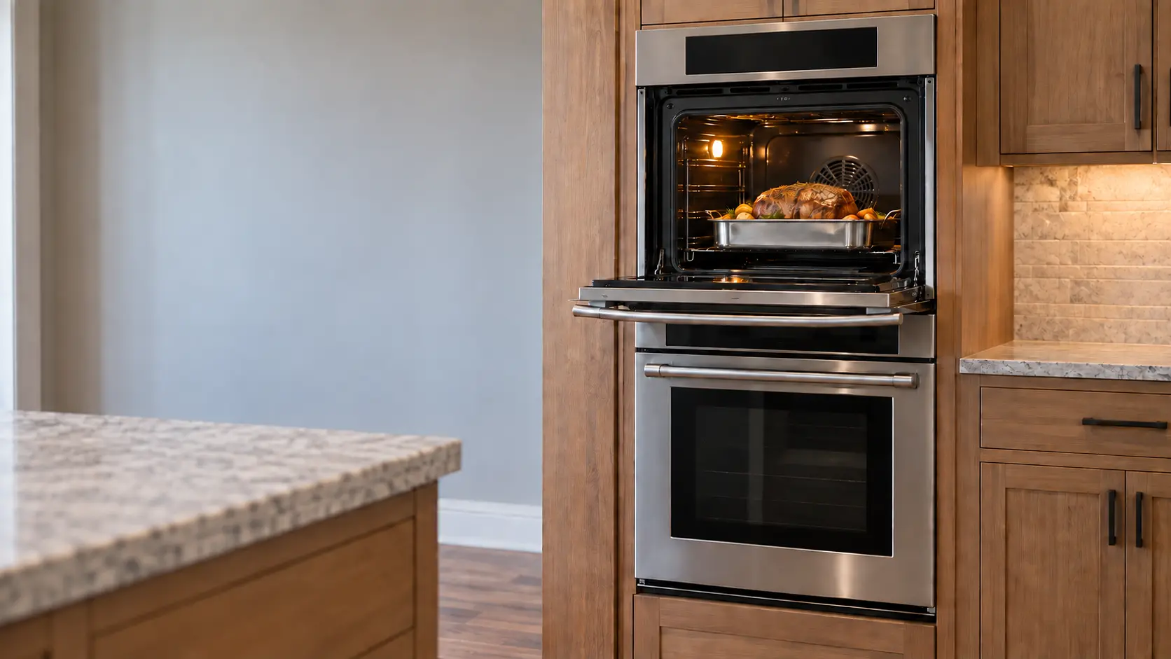 A stainless double wall oven built into tall wood cabinetry in a US home kitchen, the upper door open with a roast inside and the lower door closed.