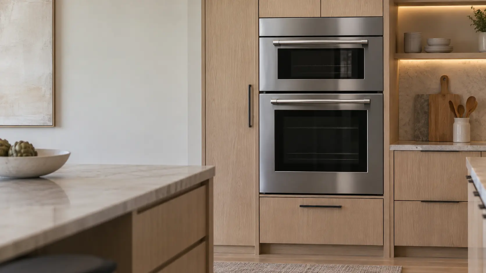 A built-in wall oven in a coastal San Diego kitchen with a steam oven stacked over a wall oven in light oak cabinets, seen square on from across the room.